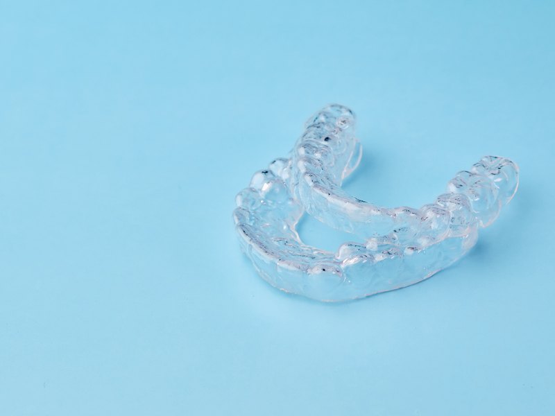 Dentista sosteniendo una férula de descarga transparente en la consulta