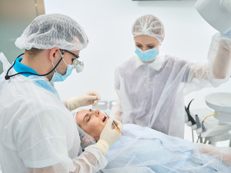 Equipo de cirugía oral atendiendo a un paciente en el quirófano de la clínica