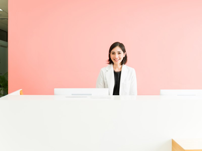 Recepcionista atendiendo a una paciente en el mostrador de la clínica dental
