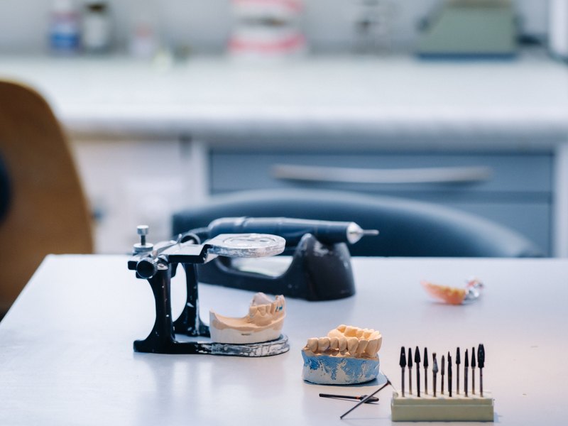 Modelos dentales, un articulador negro e instrumental de laboratorio sobre la mesa