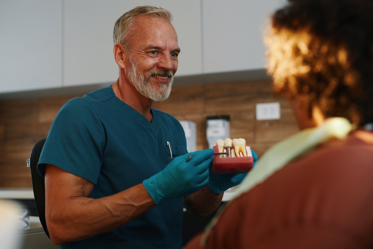 Dentista enseñando al paciente un modelo de implante dental en la consulta