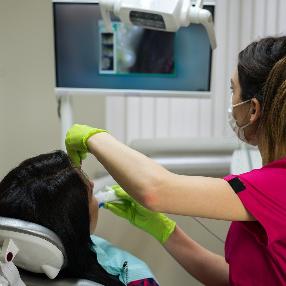 Dentista examinando la boca de una paciente con una cámara intraoral