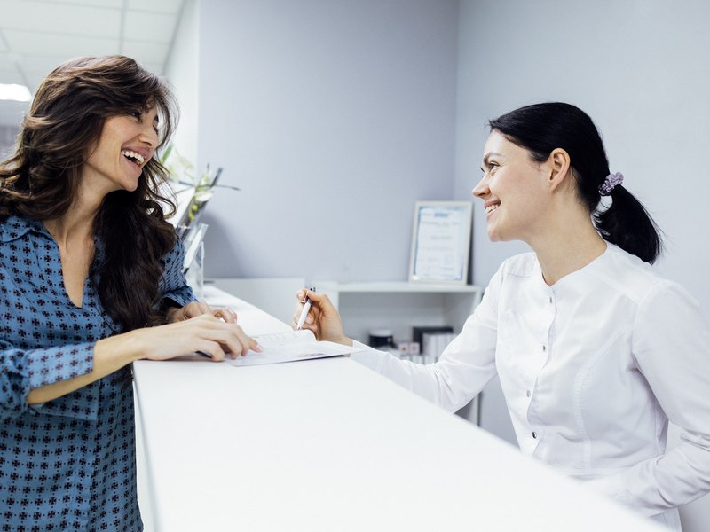 Receptionist attending a patient at the dental clinic front desk