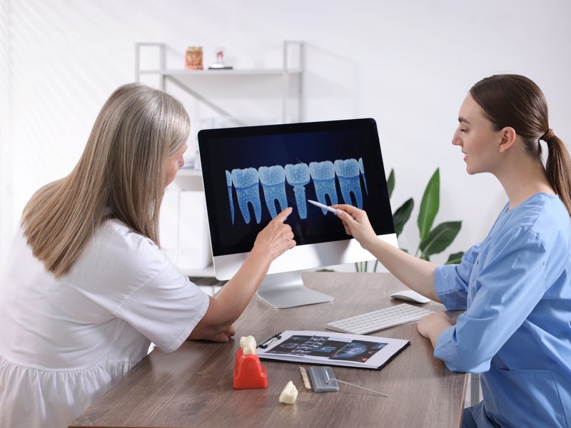 Dos profesionales de la clínica repasando una radiografía o un modelo dental en pantalla