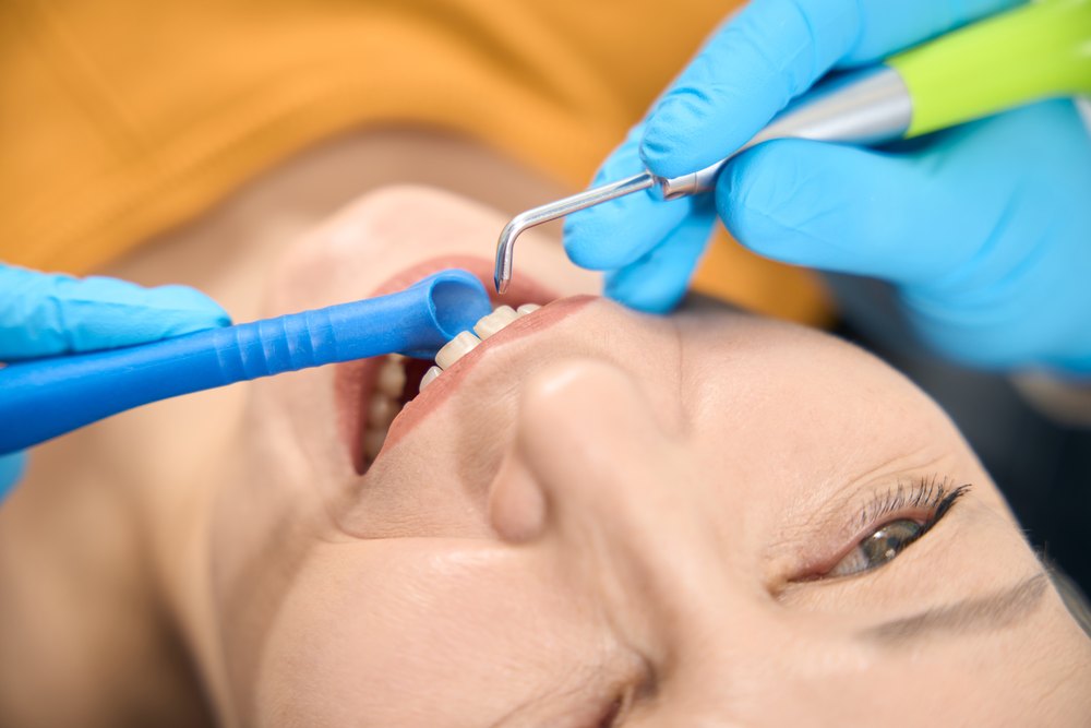 Paciente durante una limpieza dental profesional con ultrasonidos y aspiración