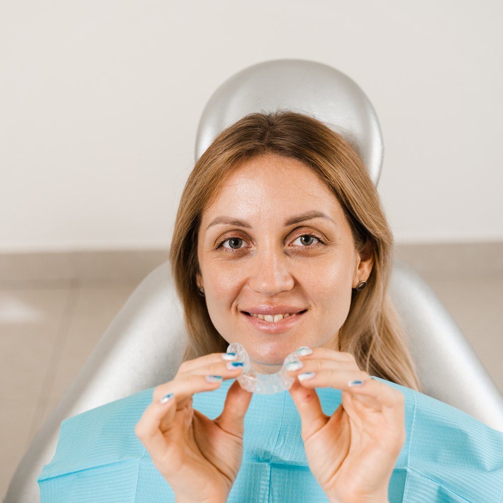 Paciente en el sillón dental enseñando su alineador transparente