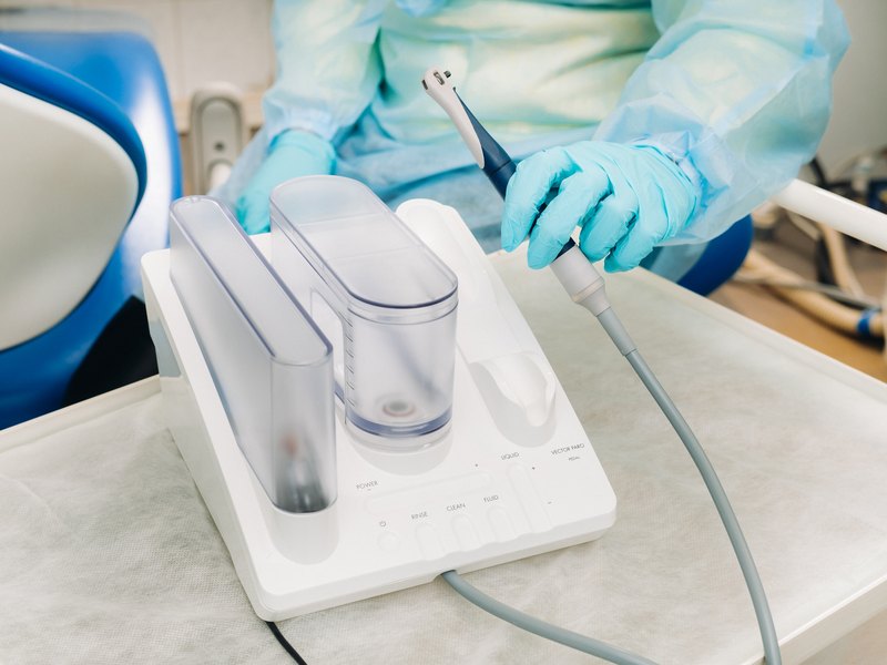 Higienista dental tratando las encías de un paciente con ultrasonidos
