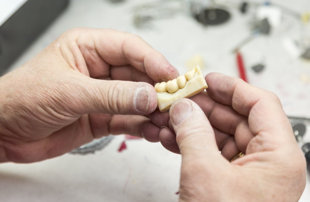 Dental technician holding a finished dental bridge