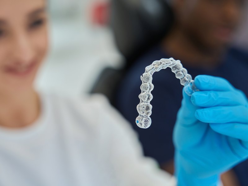 Dentista sosteniendo una férula de descarga transparente en la consulta