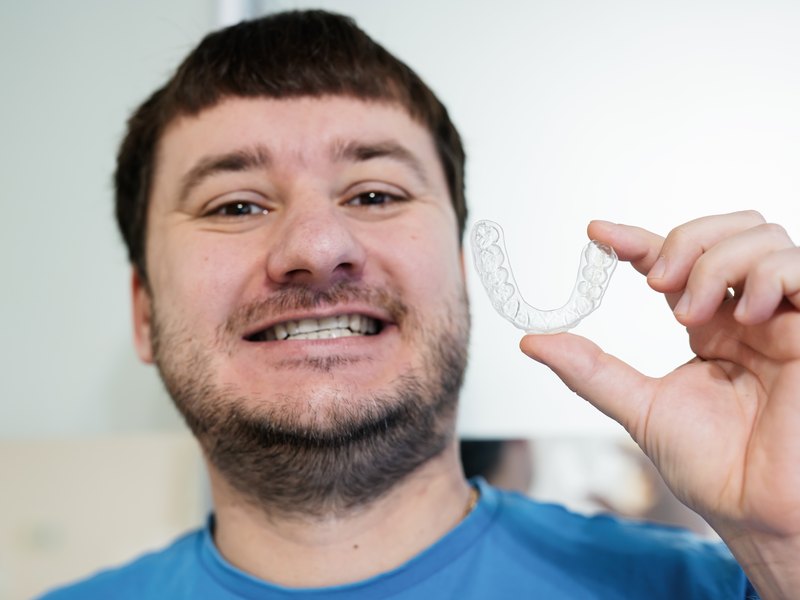 Dentista sosteniendo una férula de descarga transparente en la consulta