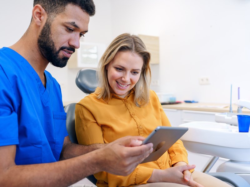 Dentista general enseñando a una paciente el resultado de su revisión en una tableta
