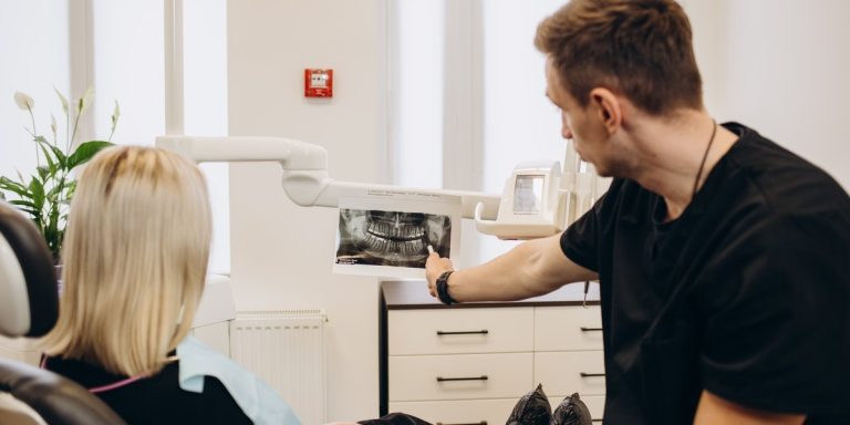 Dentist at a dental clinic showing a patient her panoramic X-ray on the screen