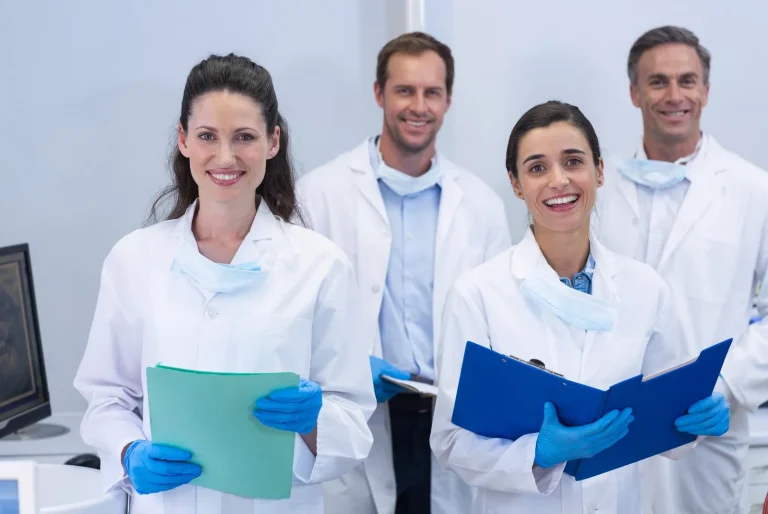 Four dental professionals in white coats, different types of dentists working together at a clinic in Barcelona