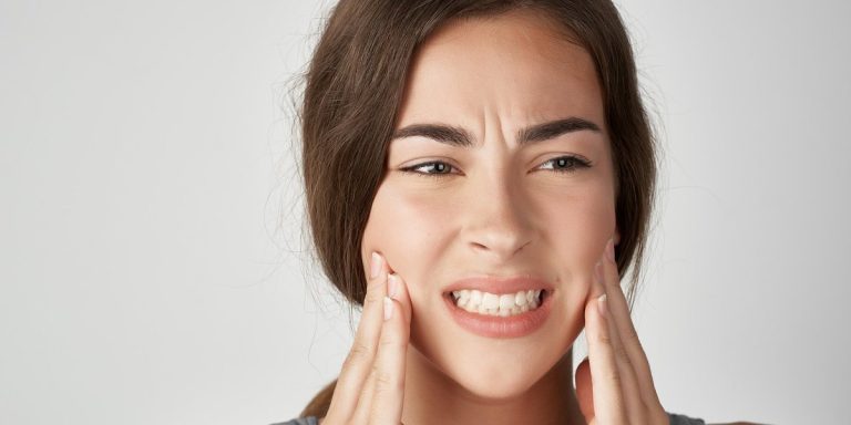 Dona amb gest de dolor subjectant-se la mandíbula amb les dues mans