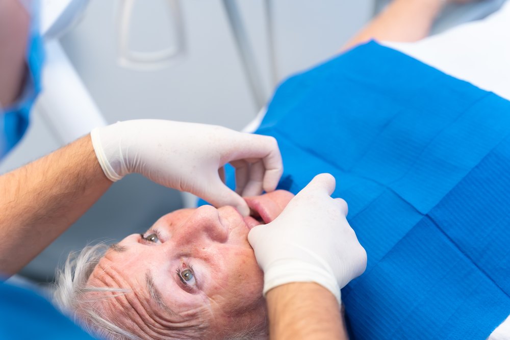 El dentista revisa les genives d'un pacient gran abans del raspat