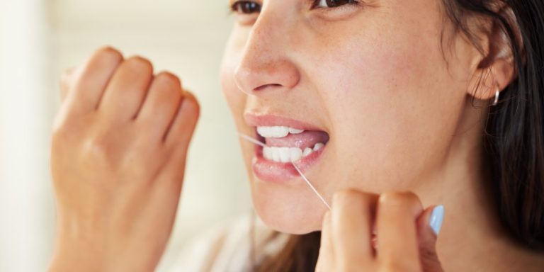 Mujer pasándose hilo dental entre los dientes