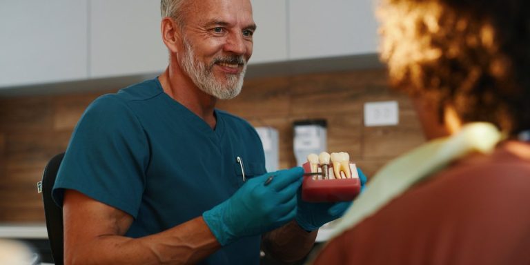 Dentista explicant a un pacient el tractament amb un model d'implants