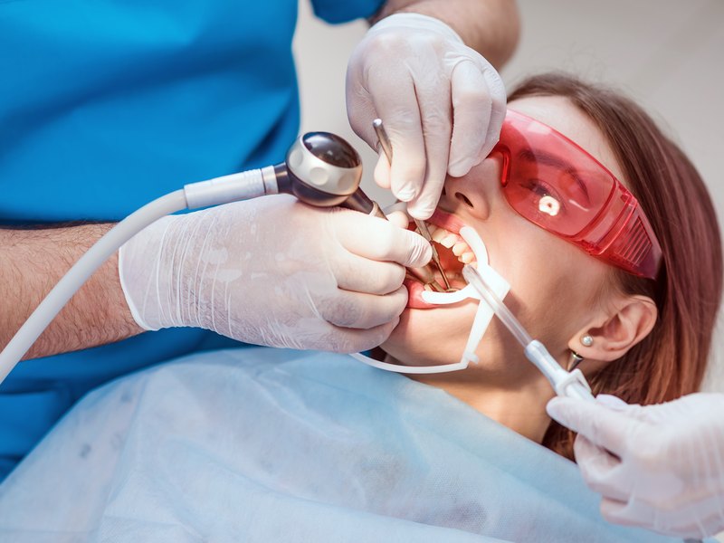 Tractament periodontal amb aspiració a una pacient amb ulleres protectores vermelles