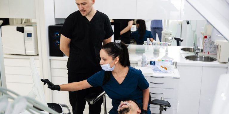Dentista i auxiliar revisen a la pantalla de la cadira l'exploració d'un pacient abans de l'extracció