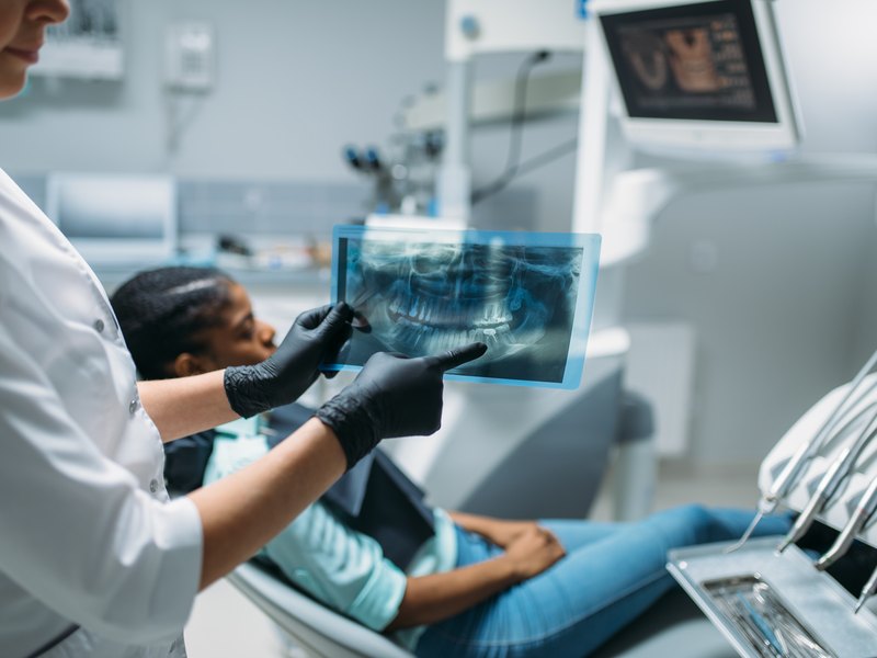 Dentista revisando una radiografía panorámica junto a la paciente en el sillón dental