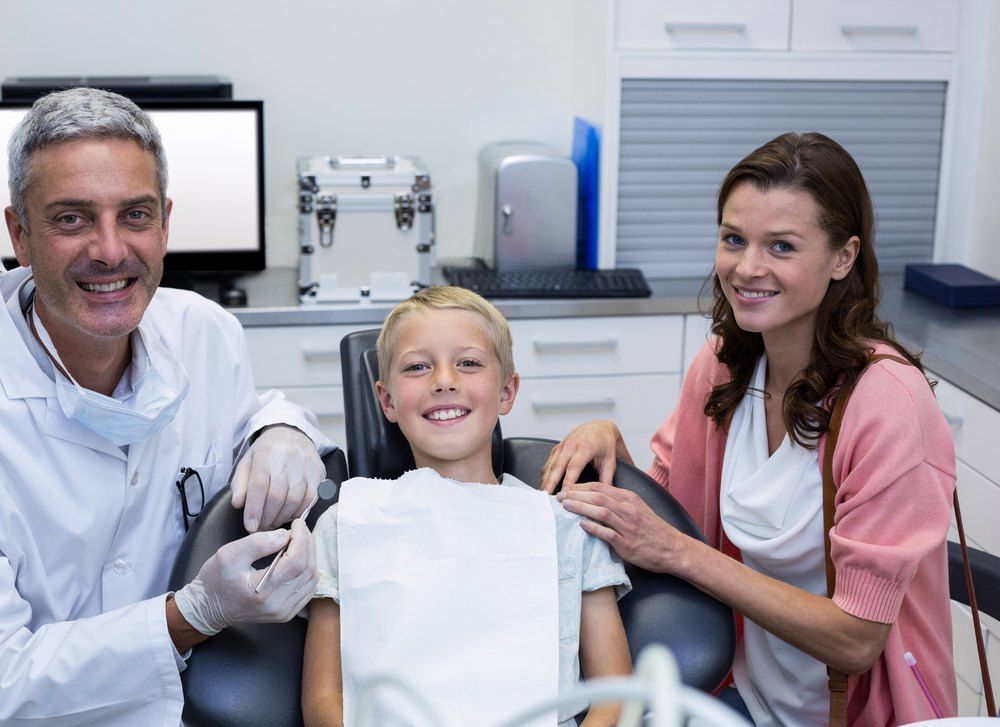 Un nen a la revisió dental amb el dentista i la seva mare