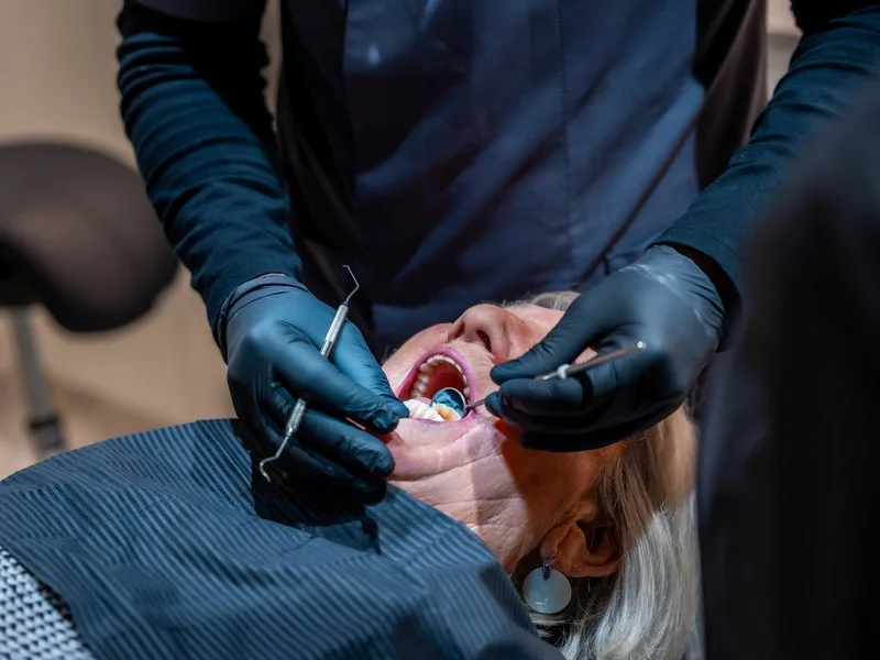 Dentist checking a patient's fillings with a mirror and probe